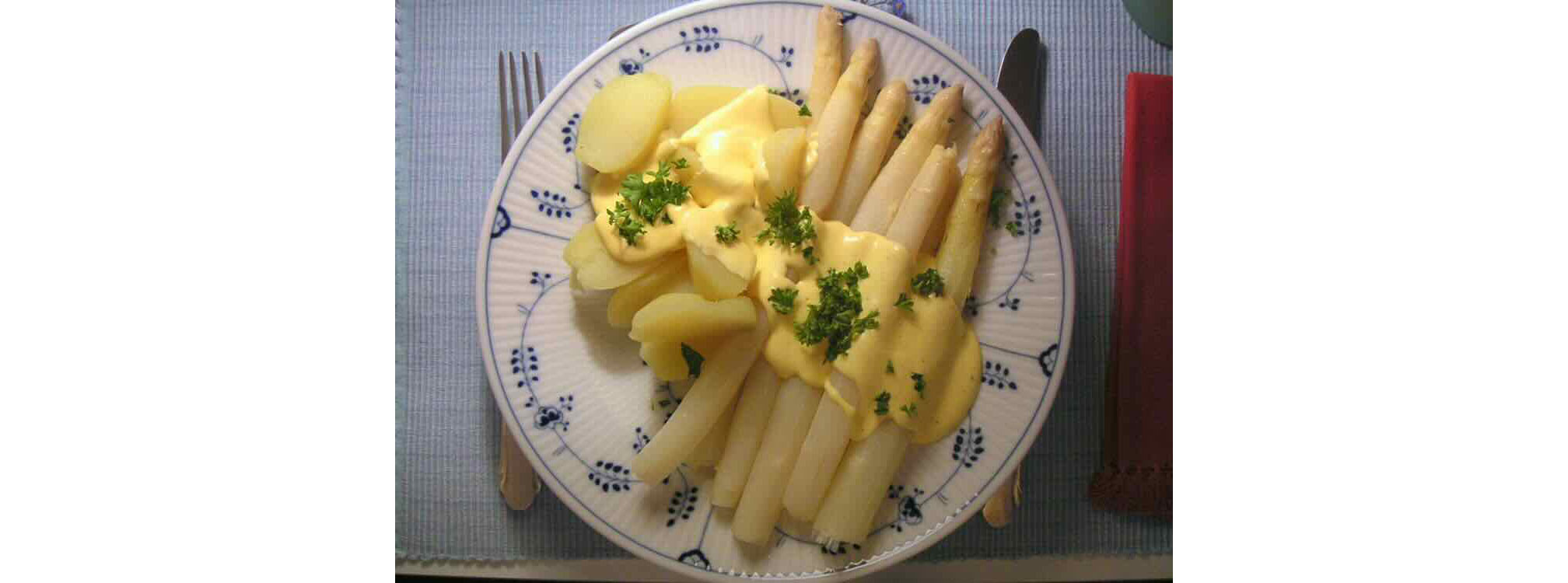 white asparagus served with potatoes and parsley topped Hollandaise sauce