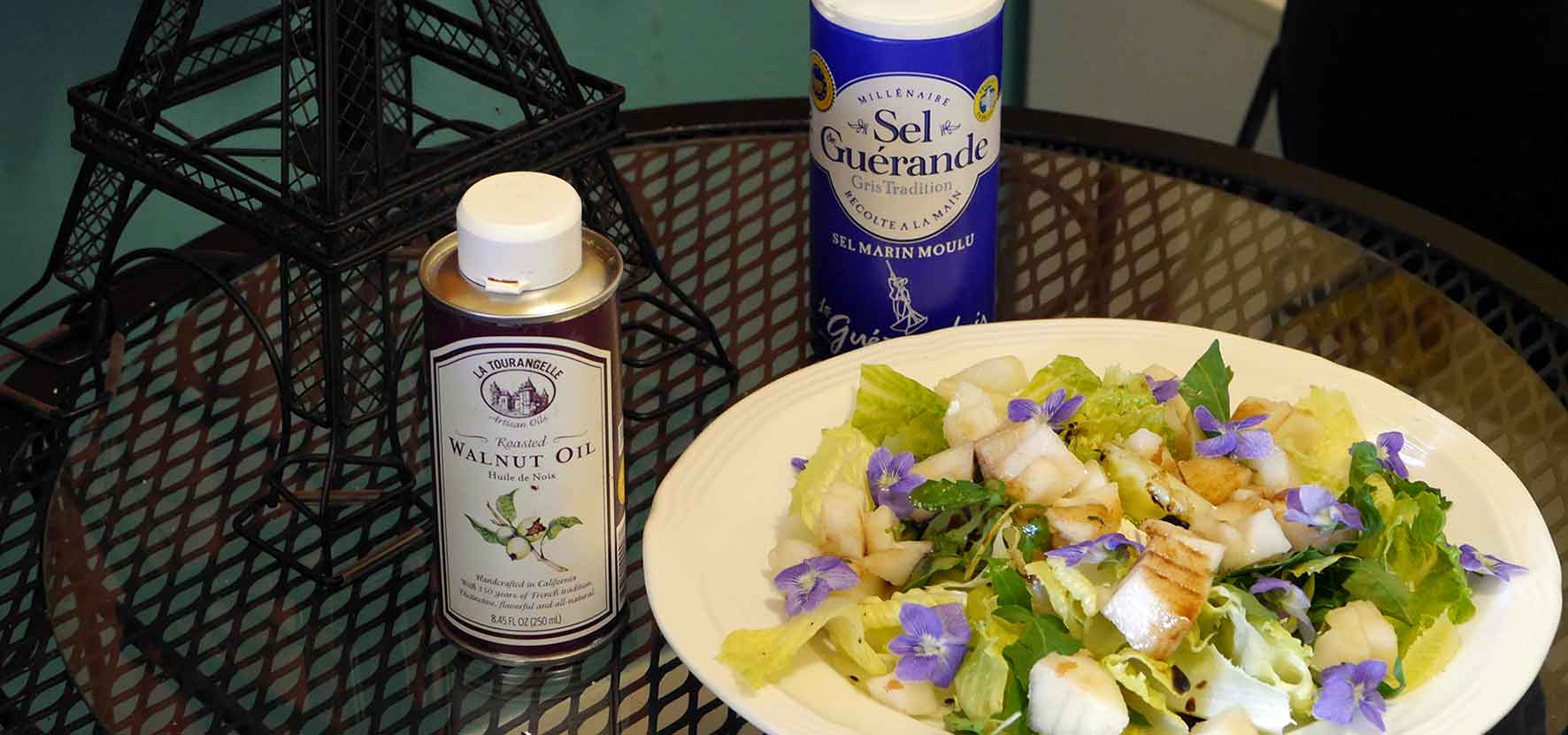 arugula, pear & wild violet salad on plate with containers of walnut oil and French sea salt