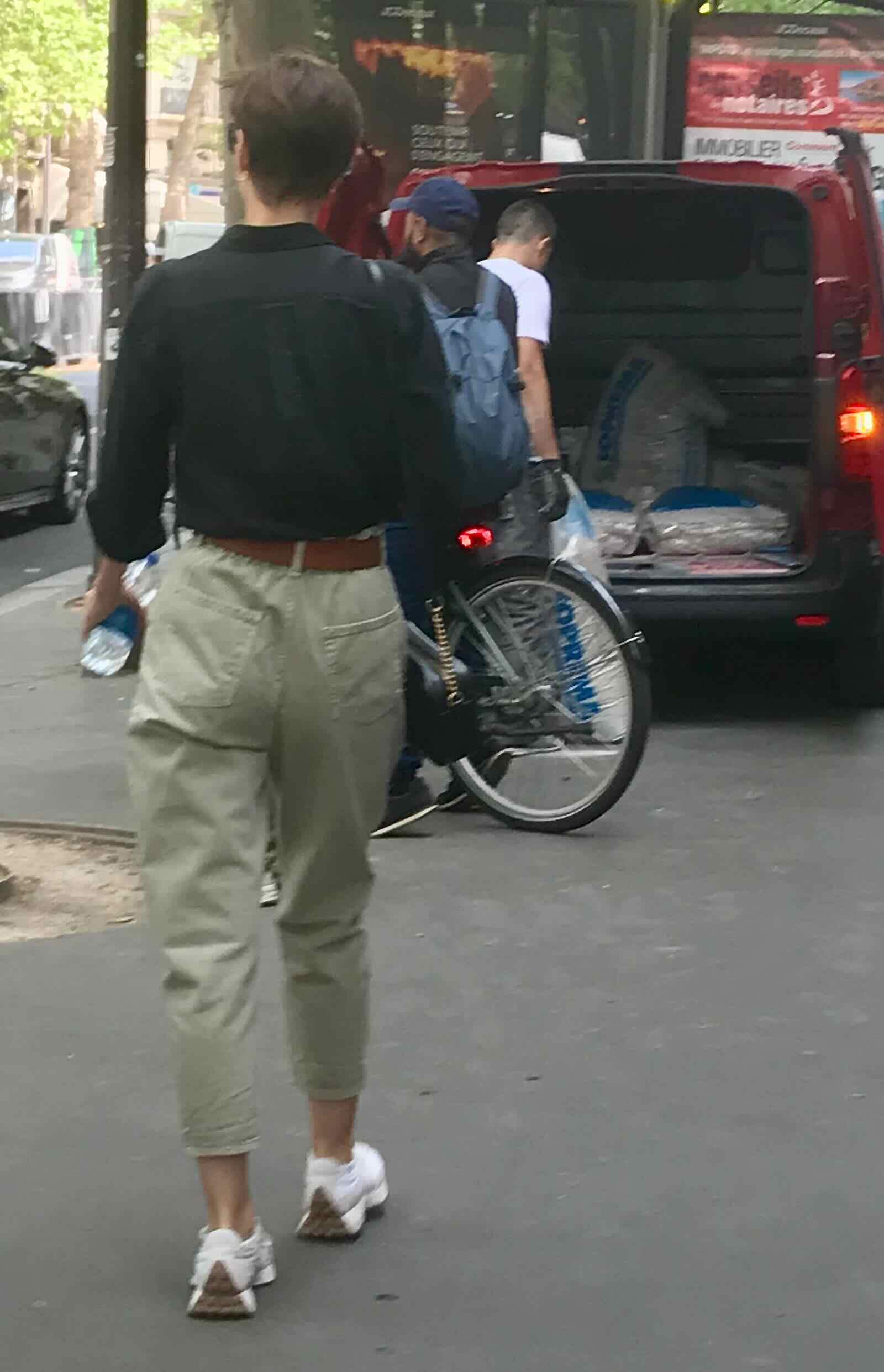 woman in black shirt and khaki pants walking along Paris street