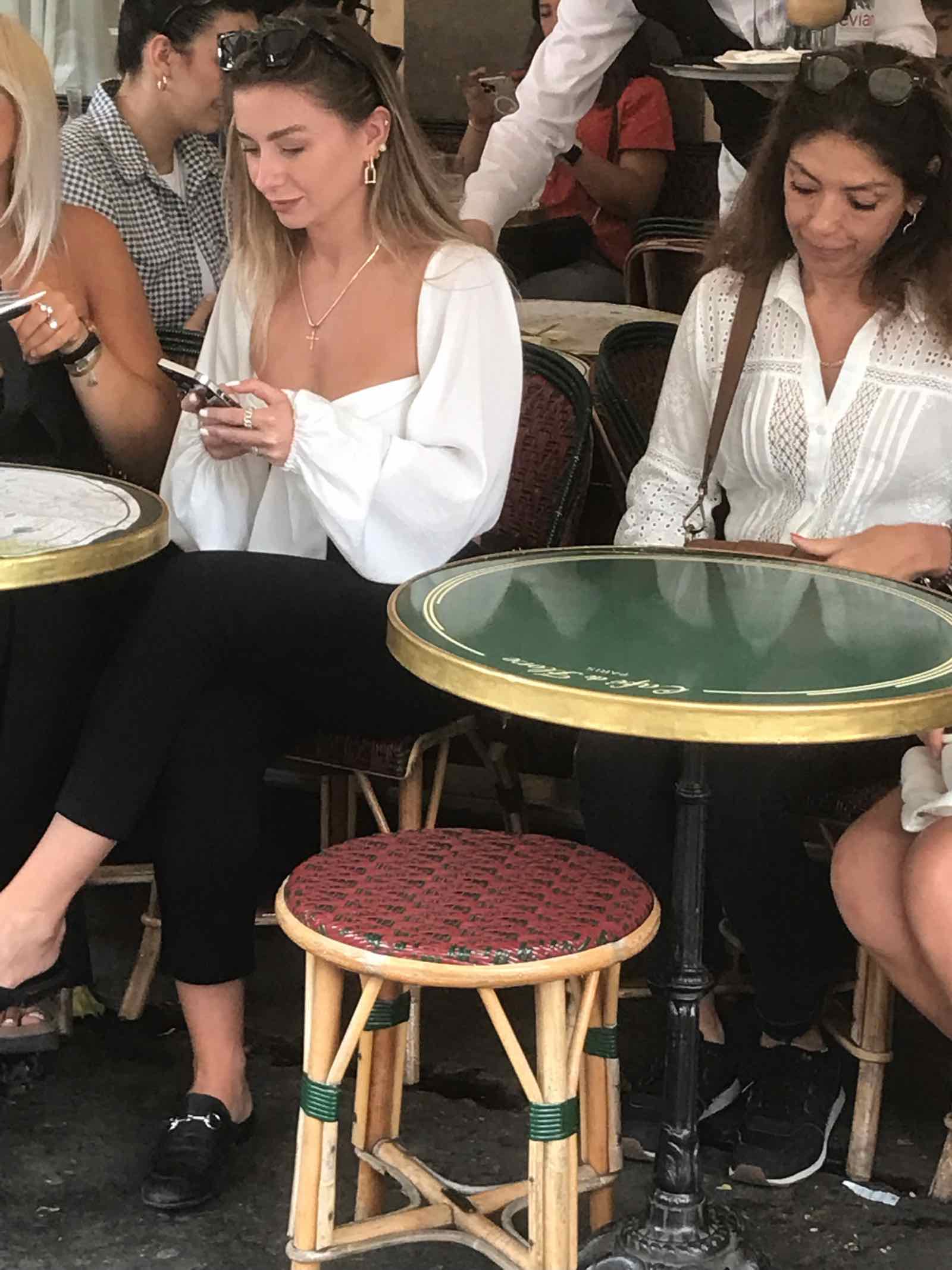 2 young women in Paris cafe looking at their phones