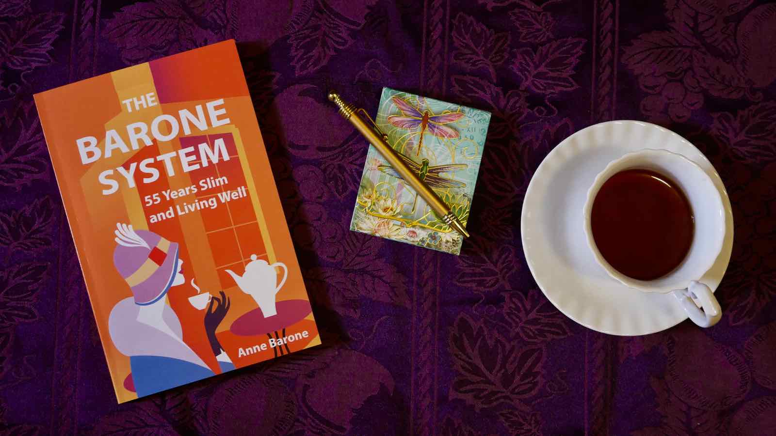 The Barone System paperback book with notepad and pen and cup of coffee